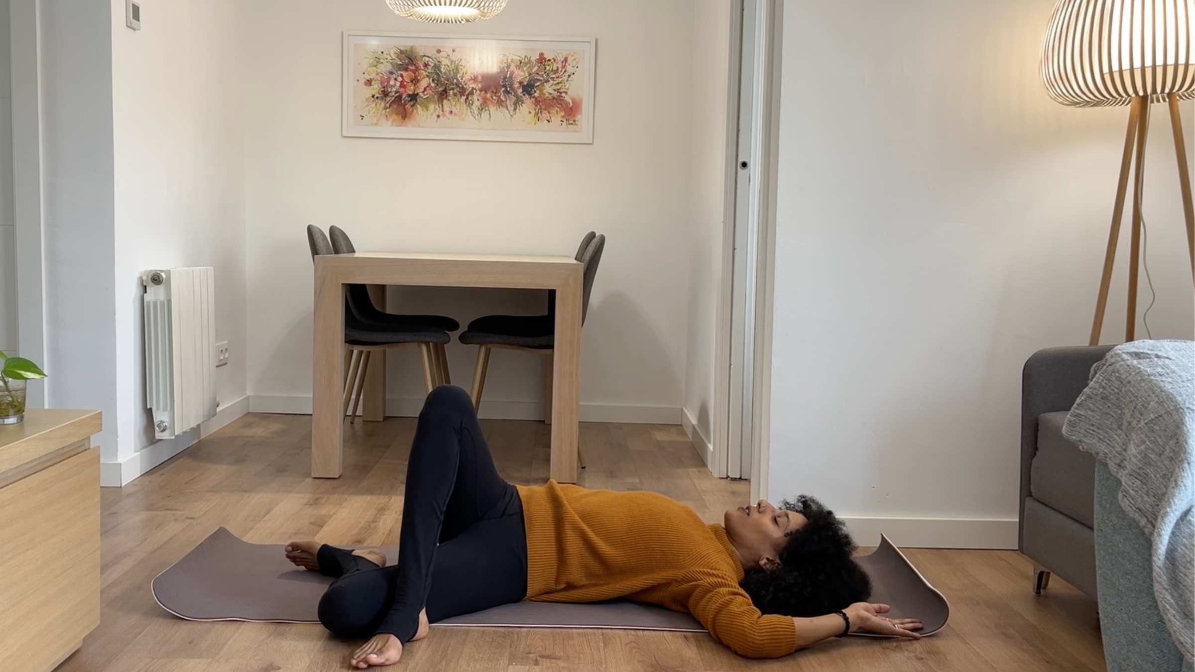 Laia Bové performing a reclined spinal twist by lowering her crossed leg across her body toward the floor.